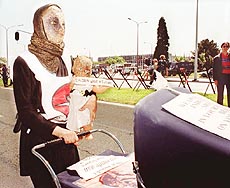 A protester in costume with a doll and carriage stands in front of NATO Headquarters in Brussels, on Thursday. 