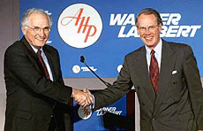 John R. Stafford, left, chairman of American Warner Inc., and Lodewijk J.R. de Vink, CEO of American Warner Inc., shake hands before a New York news conference on Thursday. 