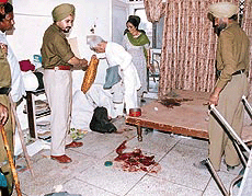 Policemen inspect the blood-stained floor and other belongings at the house where four persons were injured and robbed by a gang of miscreants on Friday night.
