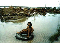 A little girl sits on an inflated tyre near her cyclone-devastated slum on the outskirts of Paradip on Friday