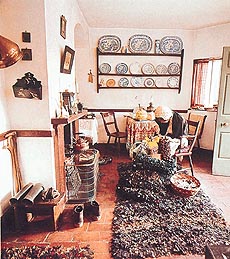 An early 19th century living room at the Shelton Tollhouse Museum. A volunteer demonstrates rug-making