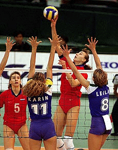 Evgenia Artamonova of Russia, second from right, hits the ball over Karin Rodrigues (11) and Leila Barros (8) of Brazil in the 1999 Women's World Cup Volleyball match