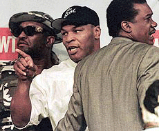 Mike Tyson is pulled away from a press conference by co-trainer Tommy Brooks, right, following a verbal exchange between Tyson and Orlin Norris' managers at the MGM Grand Hotel and Casino in Las Vegas on Wednesday