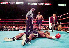 Referee Richard Steele stands over Orlin Norris, front, after Mike Tyson knocked Norris down after the bell was sounded following the end of the first round during their heavyweight bout