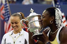 Serena Williams kisses the winners' trophy as runner-up Martina Hingis stands in the background after the U.S. Open
