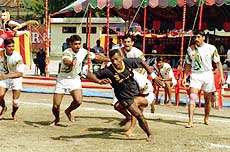 India's Kabaddi players, in white, block Sri Lankan K.P.T. Tushara, in black, during preliminary round of Kabaddi in the South Asian Games 
