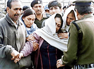 The widow of J.S. Pathania, Assistant Commandant of the Border Security Force, (C) falls unconscious as the remains of her husband are carried out of a plane from Srinagar, 15 February 2000. Pathania, who was killed in a daring raid by Muslim separatist militants near Srinagar, managed to kill two militants, one of which was later identified as top Lashkar-e-Toiba leader Irfan Ahmad, before succumbing to his wounds. — AFP photo