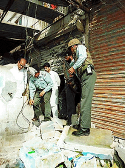 Police and officials of bomb disposal squad inspect the site of powerful explosion which destroyed a small business in Karachi, Monday. No one was injured in the explosion. Leaders of two ethnic-based parties called a one-day strike to protest massive layoffs at one of the city's biggest employers, The Pakistan Steel Mill. Police and paramilitary Rangers have been deployed throughout the city to prevent violence