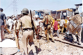 Police personnel clear unauthorised hutment along the Central Railway track at Govandi. The demolition drive is a part of the maintenance work being undertaken by the Railways. — PTI photo