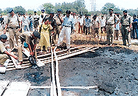 Police officials, assisted by forensic experts, attempt to extricate shoes and other material of the victim whose body was found earlier in a coal tar dump in Hallo Majra on Sunday. — Tribune photo by Parvesh Chauhan
