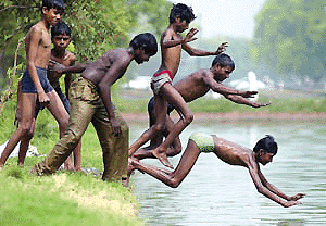 Youths jump into one of the water basins at Rajpath to escape the heat in New Delhi on Monday. The mercury has settled above 40 degrees Celsius in the Capital. — AFP