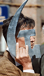 A man carries an iron hammer and a sickle symbol as he takes part in a May Day march in Kiev. — AFP