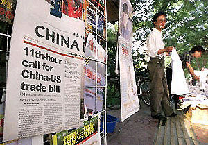 Chinas leading English daily, headlining the US House of Representatives vote for normalising trade ties with China, goes on sale in Beijing on Thursday as a street hawker sells knock-off designer brand T-shirts. 