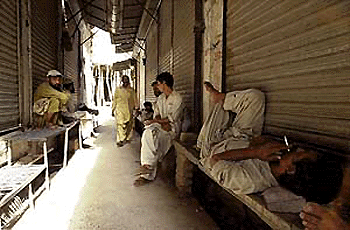 Labourers take rest in the shadows of downed shutters at a market in Rawalpindi city, some 25 km from Islamabad, on Monday. All major markets were closed as traders observed a strike against the national tax survey launched by the military regime.  AFP