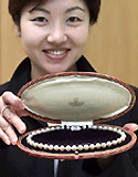 An employee of K.Mikimoto and Co. Ltd. shows off a pearl necklace given to US actress Marilyn Monroe by American baseball player Joe DiMaggio during their 1954 honeymoon. The copy of the  necklace, priced at 1 million yen (US $ 9,300) is currently on sale.  AFP photo