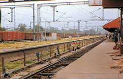 A Baba sitting on the platform no.5 and some persons having a bath at a rail hydrant.