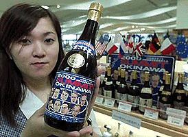 Liquor store clerk Chie Oyakawa holds a bottle of Okinawa Summit 2000 Awamori, a local liquor of the southern Japanese island of Okinawa, which is on display at Naha Airport on Friday. The local drink Awamori is made from rice and the commemorative bottles have been emblazoned with drawings of the leaders of the Group of Eight nations.  Reuters