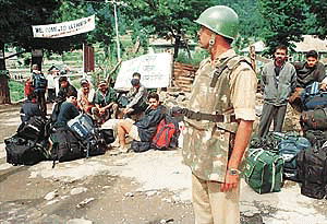 A para-military jawan stands guard as a group of pilgrims waits for a bus at Pahalgam,  97 km south-east of Srinagar,  on Wednesday.  Reuters photo.