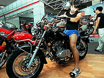 A young man tries out a new foreign type of motorbike produced by a Chinese factory, at a motorbike trade show in Shanghai in Wednesday. Foreign companies are planning to increase their China investments after China's expected entry into the WTO  AFP photo
