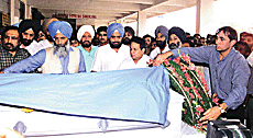 Harshmohan Singh, son of the late football Olympian Jarnail Singh, lays a wreath on the body of his father, at IGI Airport in New Delhi on Saturday. Sports Minister Sukhdev Singh Dhindsa.