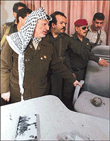 Palestinian President Yasser Arafat points to an unexploded shell that landed on a commander's chair during a tour to the rocketed headquarters of his force 17 security service in Gaza Strip on Tuesday .  Reuters photo