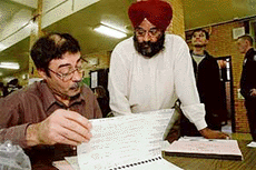 Poll inspector Hector Martinez (left) searches for Sucha Singh's name in a voter registration list in the Queens Borough of New York on Tuesday.