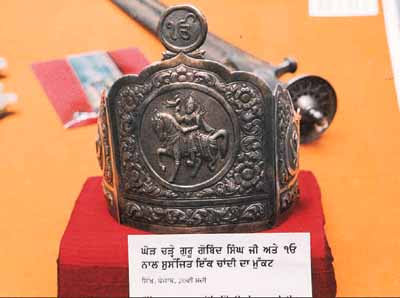 A silver crown depicting the tenth Sikh Guru, Guru Gobind Singh, riding a horse. 