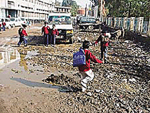 Students of Shri Atma Nand Jain Senior Secondary School, Daresi Road, make their way through garbage dumps and slush outside the main gate.