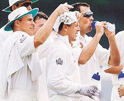 Englands wicketkeeper Alec Stewart (C) has a wet towel placed on his head by Paul Nixon during the first days play of the first Test against Sri Lanka at the Galle International Cricket Stadium on Thursday. 