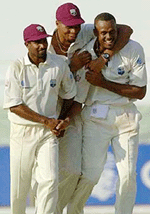 Courtney Walsh of the West Indies (right) walks off the field with Dinanath Ramnarine (left) and Meryvn Dillon, (centre) after Walsh picked up his sixth wicket 