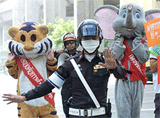 A Thai policemen directs traffic on a busy Bangkok street on Friday as his colleagues, dressed as a tiger and elephant, stand by to help promote a road safety campaign.