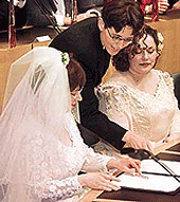 Helene Faasen (left) and Anne-Marie Thus are instructed how to sign their wedding certificate during the worlds first gay marriage in the Amsterdam town on Sunday.