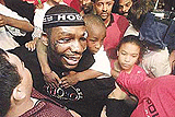 Hasim The Rock Rahman carries his cousin Marcquis Wilson (6) on his shoulder as he makes his way through a throng of wellwishers inside a sporting store in downtown Baltimore on Monday as he returned from South Africa where he knocked out Lennox Lewis to take two heavyweight titles.