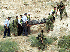 Israeli soldiers and policemen carry the body of a Jewish settler near the settlement of Takoa in the Jadean Desert on Wednesday. The bodies of two teenaged boys from a West Bank Jewish settlement were found in a cave in the Judean Desert on Wednesday, and Israeli police said it suspected Palestinians had stoned them to death. 