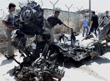 Palestinians examine the remains of Palestinian intelligence officer Abdel-Karim Oweis' car after it was hit by a Israeli missiles in the West Bank town of Jenin, on Saturday