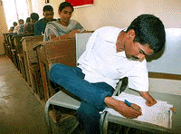 Shanker, 22, writes on a piece of paper with his foot during an exam at Moinabad in Andhra Pradesh on Saturday.