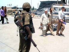 A BSF jawan watching pedestrians after a grenade explosion at Batmaloo Bus Stand in central Srinagar in which four persons including two women were killed and 18 others were injured on Monday. 