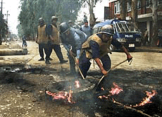 Nepalese riot police remove burning tires from a street in Kathmandu June 5, 2001. 