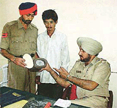 A police official shows a thermos bottle used by the accused (centre) for drug trafficking in Ludhiana on Friday. 