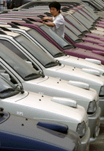 A Chinese car dealer looks at a fleet of cars produced in a joint venture between Japan and China at an outdoor auto market in Beijing on Friday. 