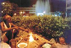 A labourer cooks his meagre meal at the backdrop of a five-star hotel at Bhaiwala Chowk, Ludhiana. 