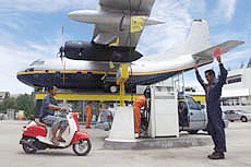A petrol pump attendant guides a motorcyclist to a pump at a gas station on a suburb east of Bangkok on Friday.