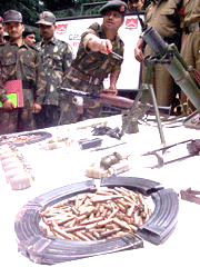 An army officer points towards the arms and ammunitions recovered after a gun battle in a camp at Chattarnar village, in Bandipura, 88 kms north of Srinagar on Saturday.