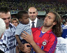 AS Roma striker Gabriel Batistuta of Argentina plays with a child from Africa at the end of a charity benefit soccer match for African children, played by a team composed of world-class drivers against another of singers and musicians in Genoa, northern Italy, on Monday.