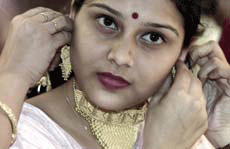 A shopkeeper helps a customer wear gold ornaments during a gold ornaments exhibition in Kolkata.