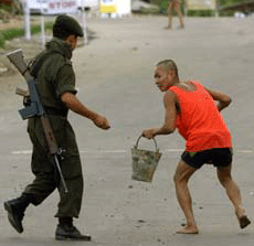 A paramilitary trooper belonging to Manipur Rifles chases away a resident who came on the street during curfew in Imphal on Wednesday.