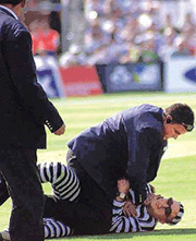 A plain clothed security man detains a fan dressed as a prisoner, who invaded the pitch, at the end of the three-nations one-day tournament match won by Australia over England, at The Oval, London, on Thursday.