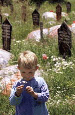 An ethnic Albanian child holds flowers at the cemetery of the Kosovo village of Izbica on Sunday.