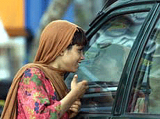 A girl smiles as she knocks at the window of a car to beg in a market in Islamabad on Wednesday.