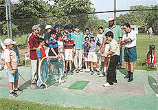 A young golfer tries his grip at the Driving Range in Chandigarh Golf Club, as the coach and others look on. 